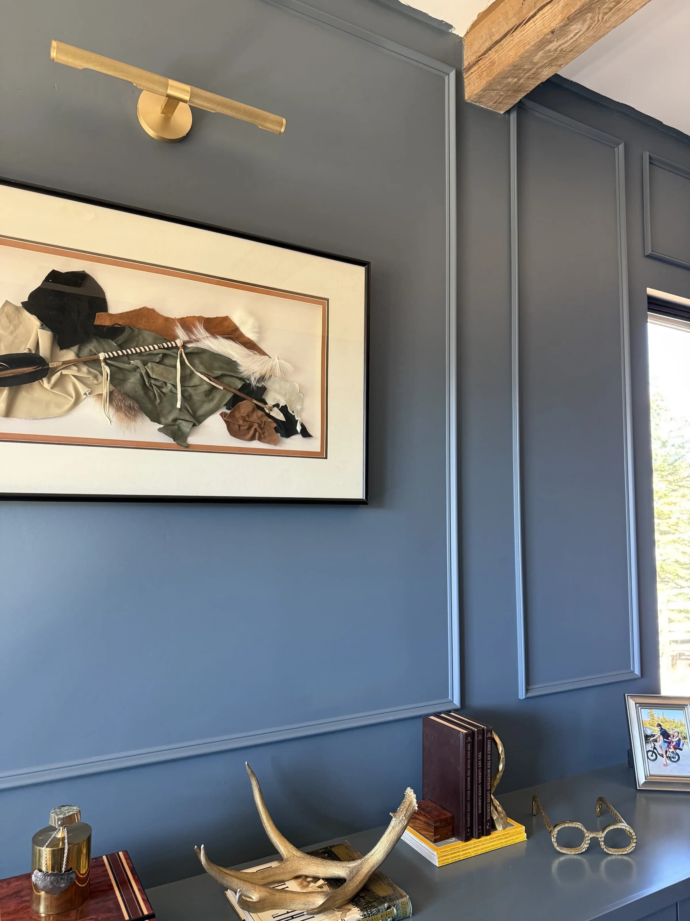 Navy paneled home office with framed art and brass picture light by BK Toolbox
