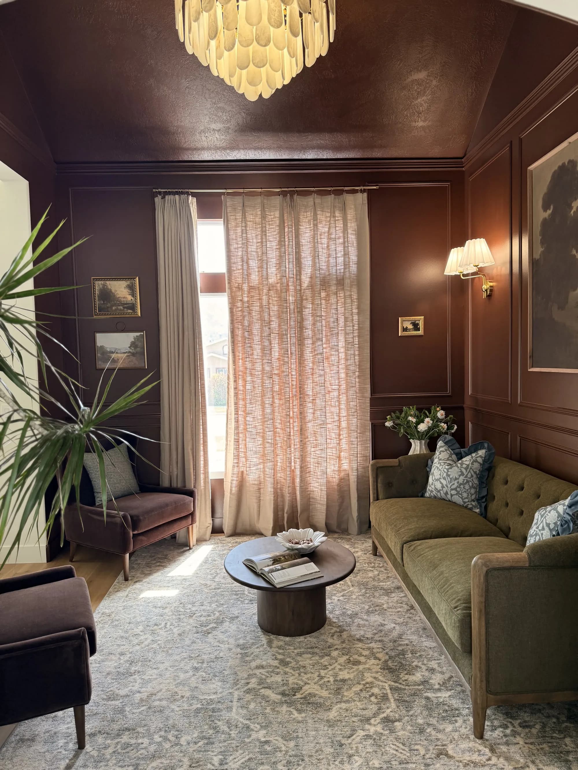 Terracotta paneled sitting room with curtains and green velvet sofa by BK Toolbox