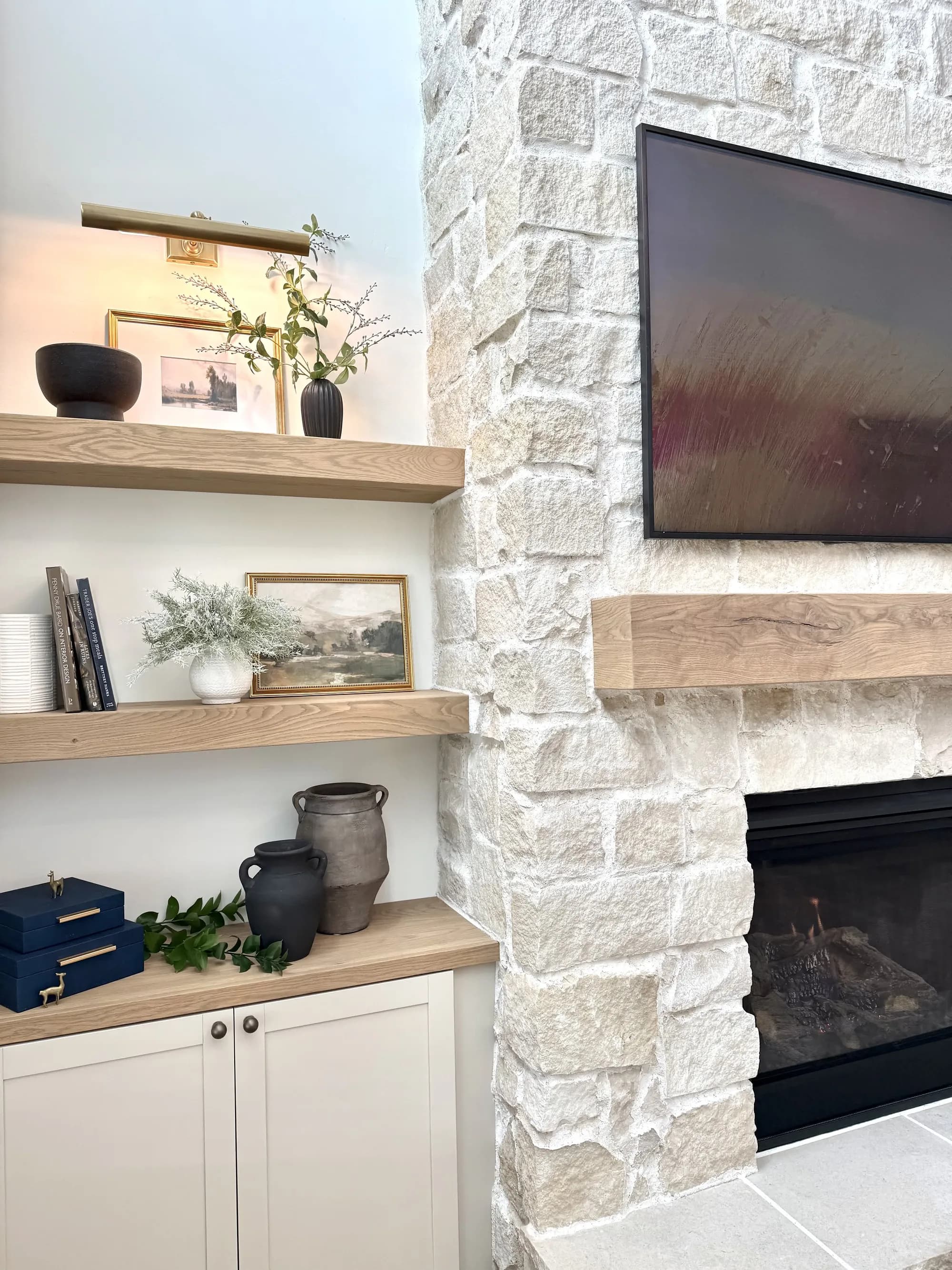 White oak floating shelves styled beside a stone fireplace by BK Toolbox