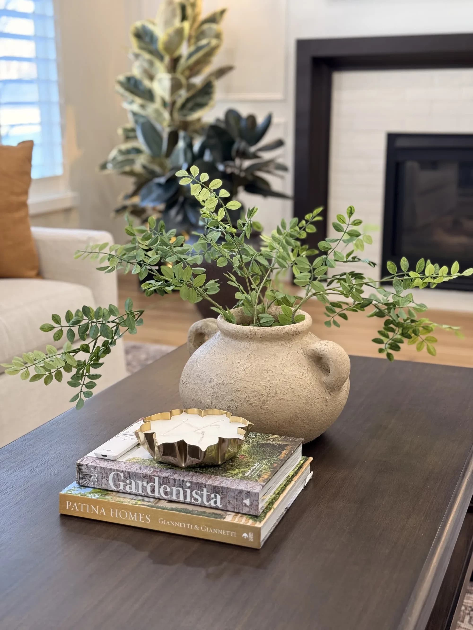 Coffee table styling with a potted plant and book near a white fireplace by BK Toolbox