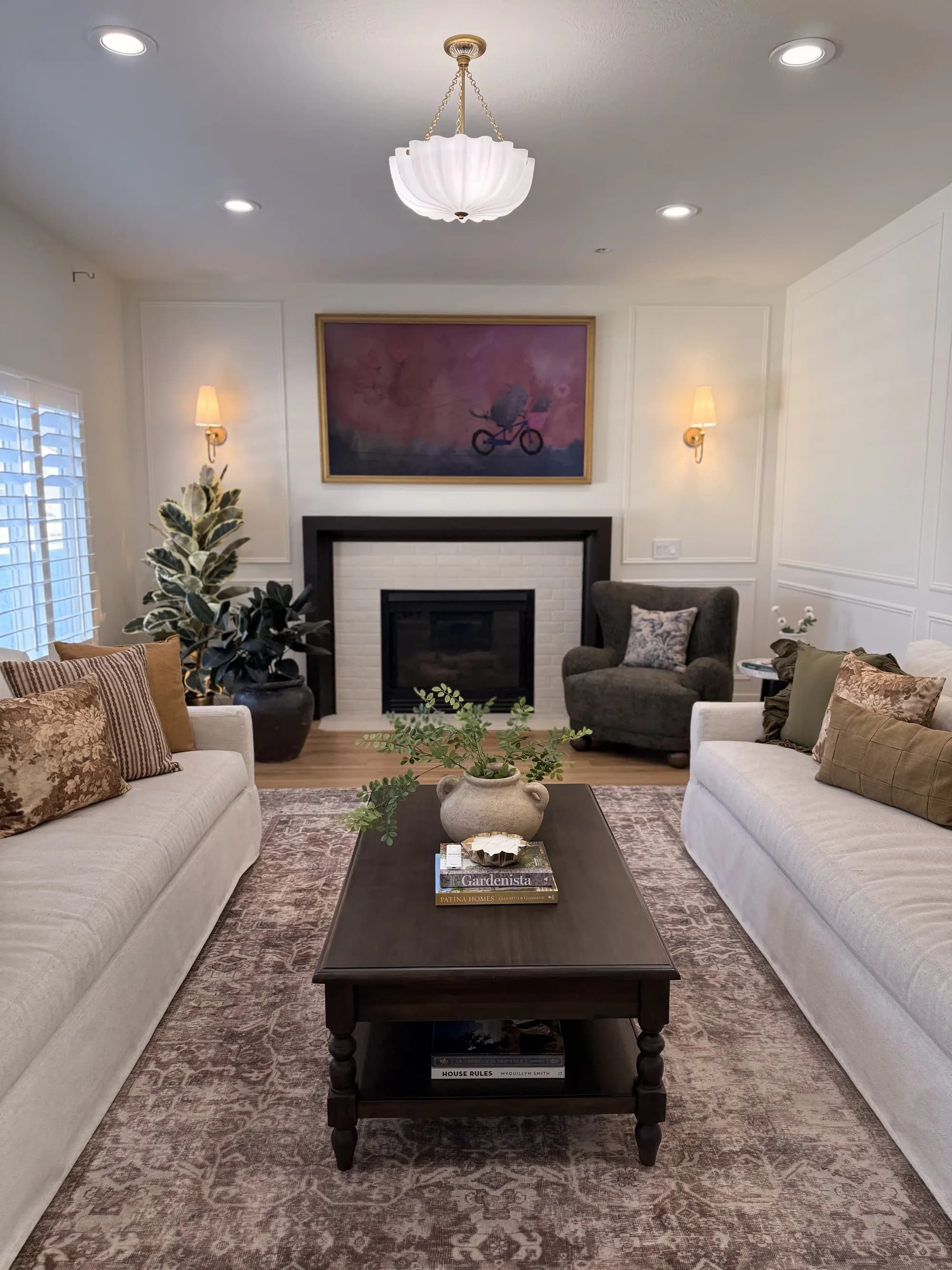 Living room with white fireplace, landscape art, and symmetrical sofas by BK Toolbox
