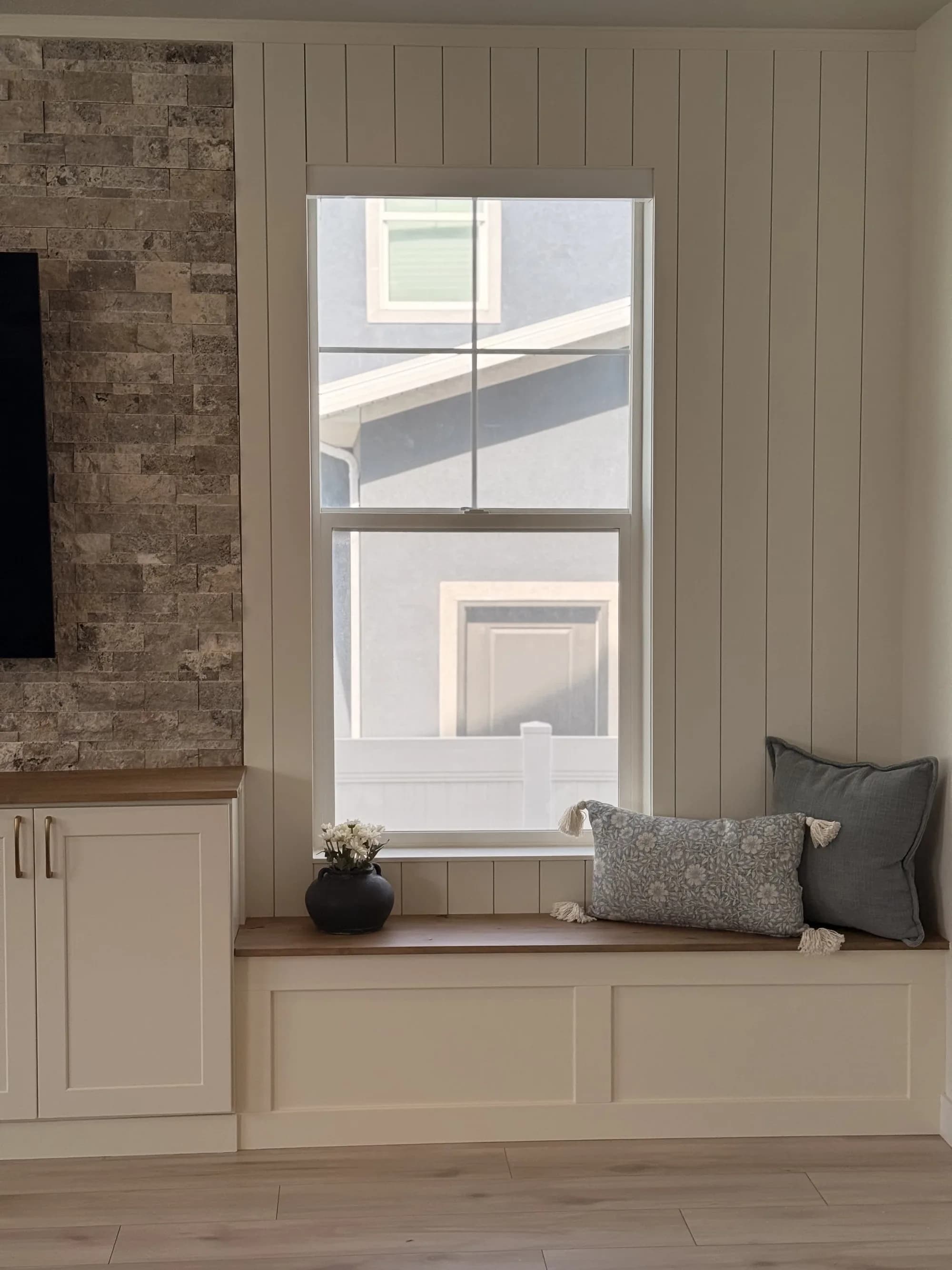 Built-in window bench beside a stone accent wall by BK Toolbox