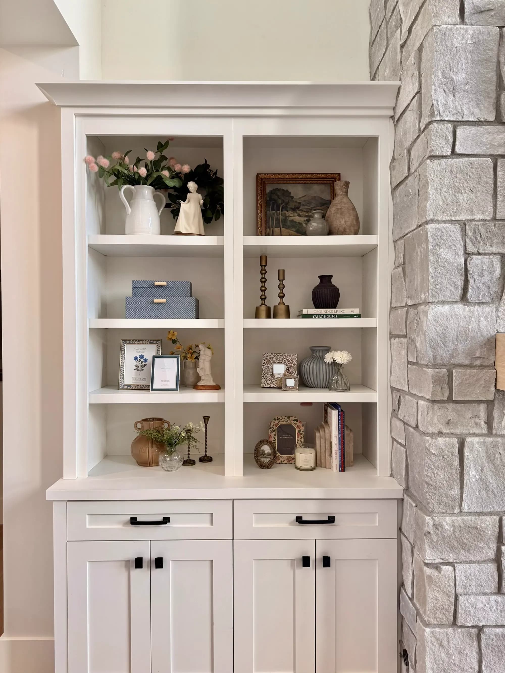 Custom white built-in shelving and cabinetry styled with art and ceramics by BK Toolbox