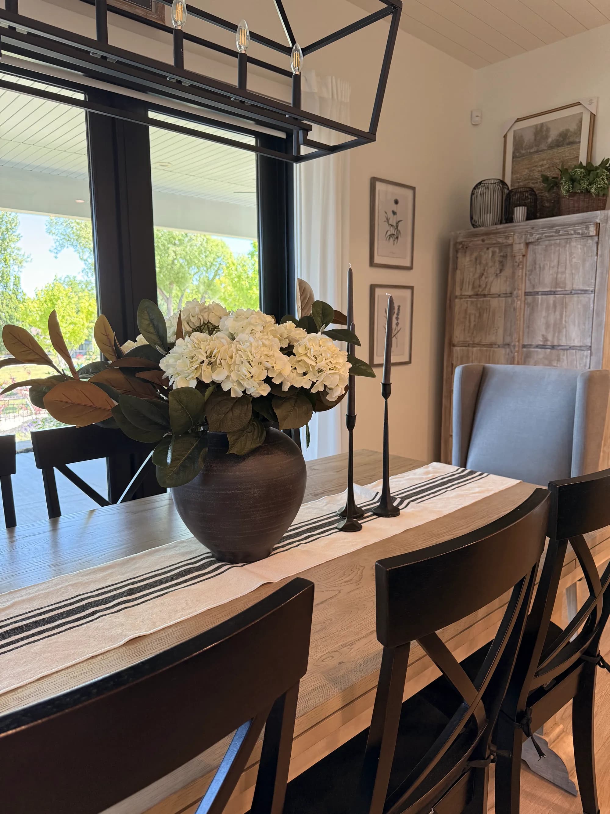 Dining room with black chandelier, wood cabinet, and styled table by BK Toolbox