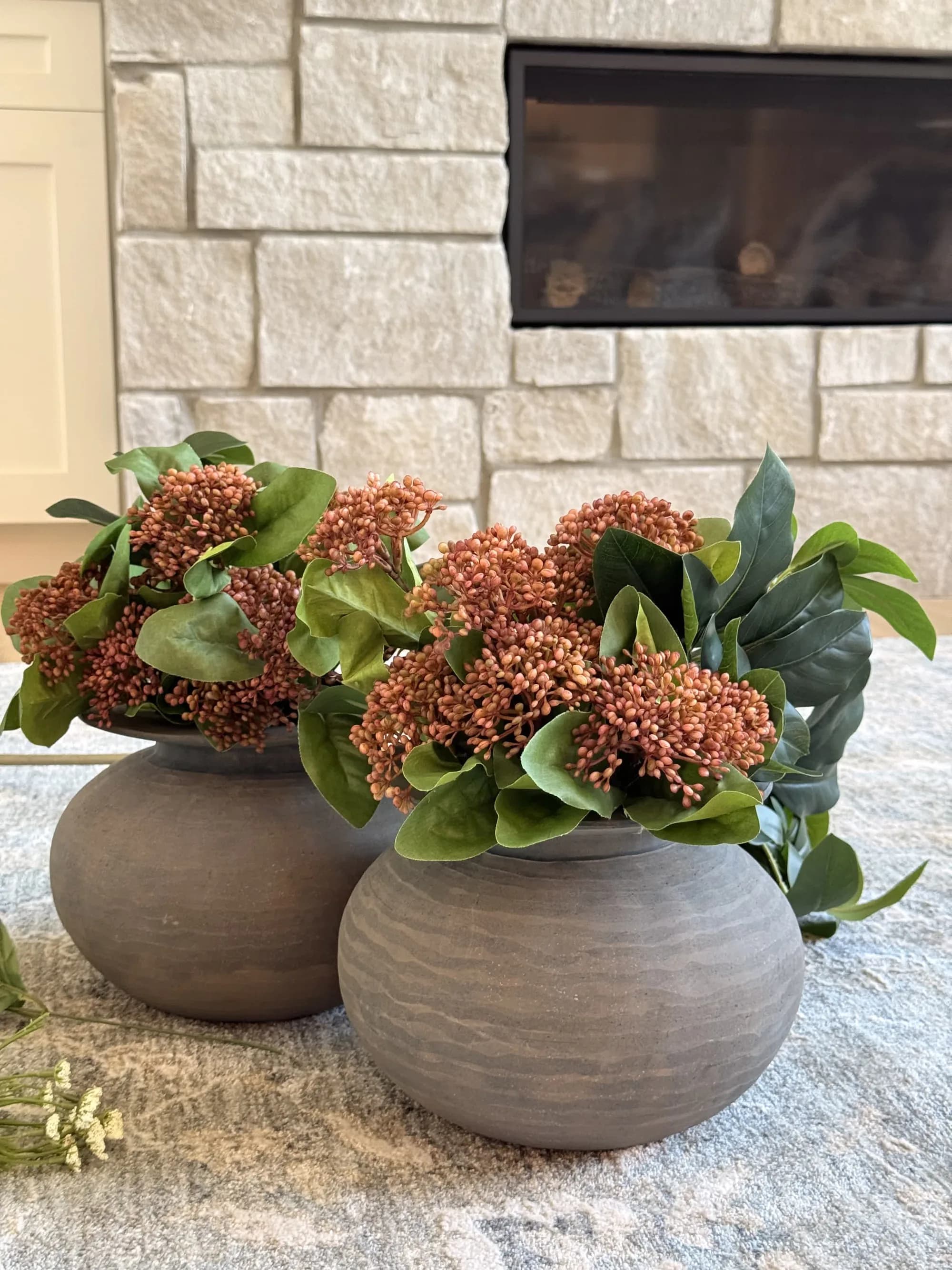 Family room with a stone fireplace styled with rust hydrangeas by BK Toolbox