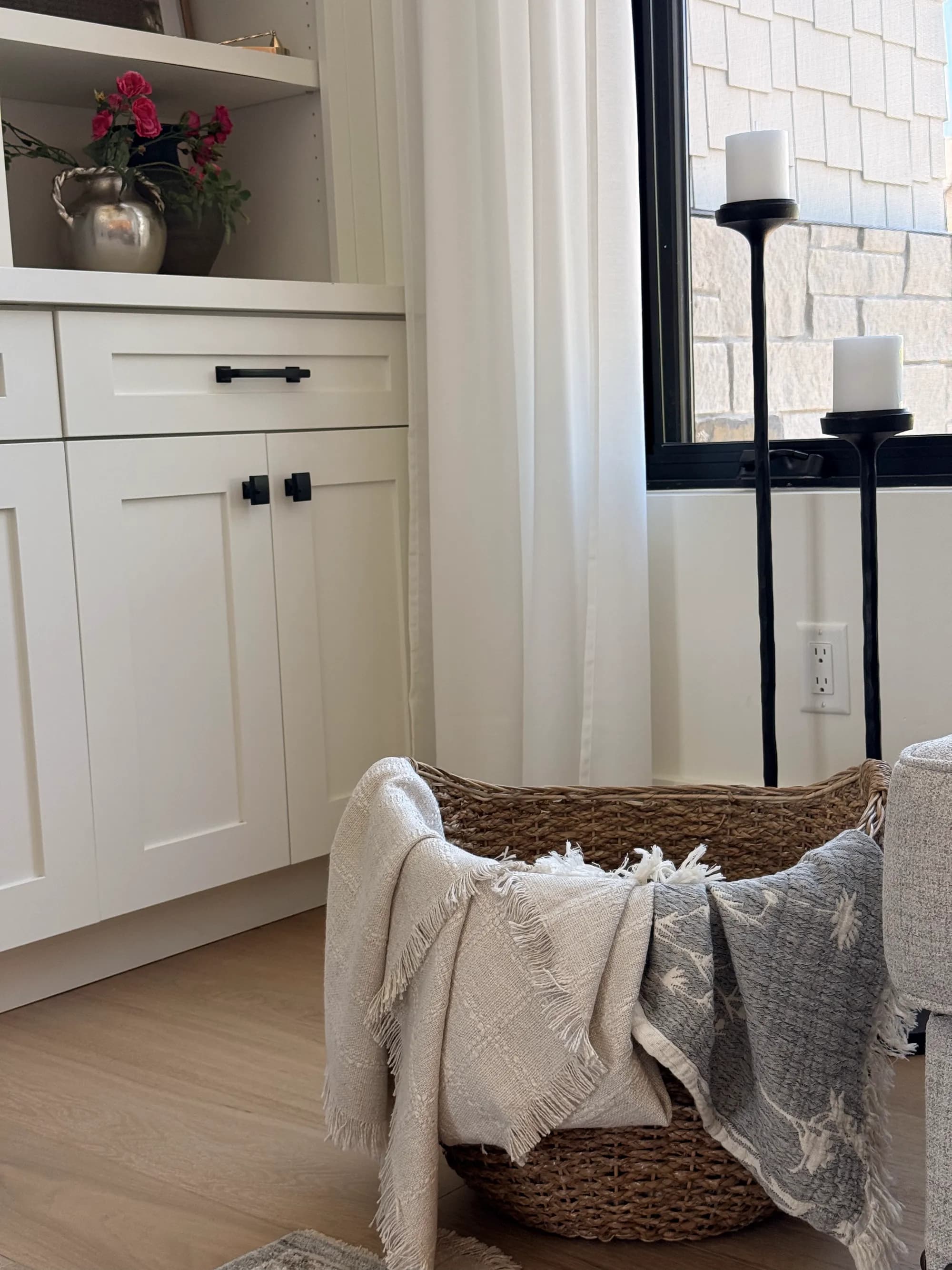 Cozy corner with a basket of throws beside a stone fireplace by BK Toolbox