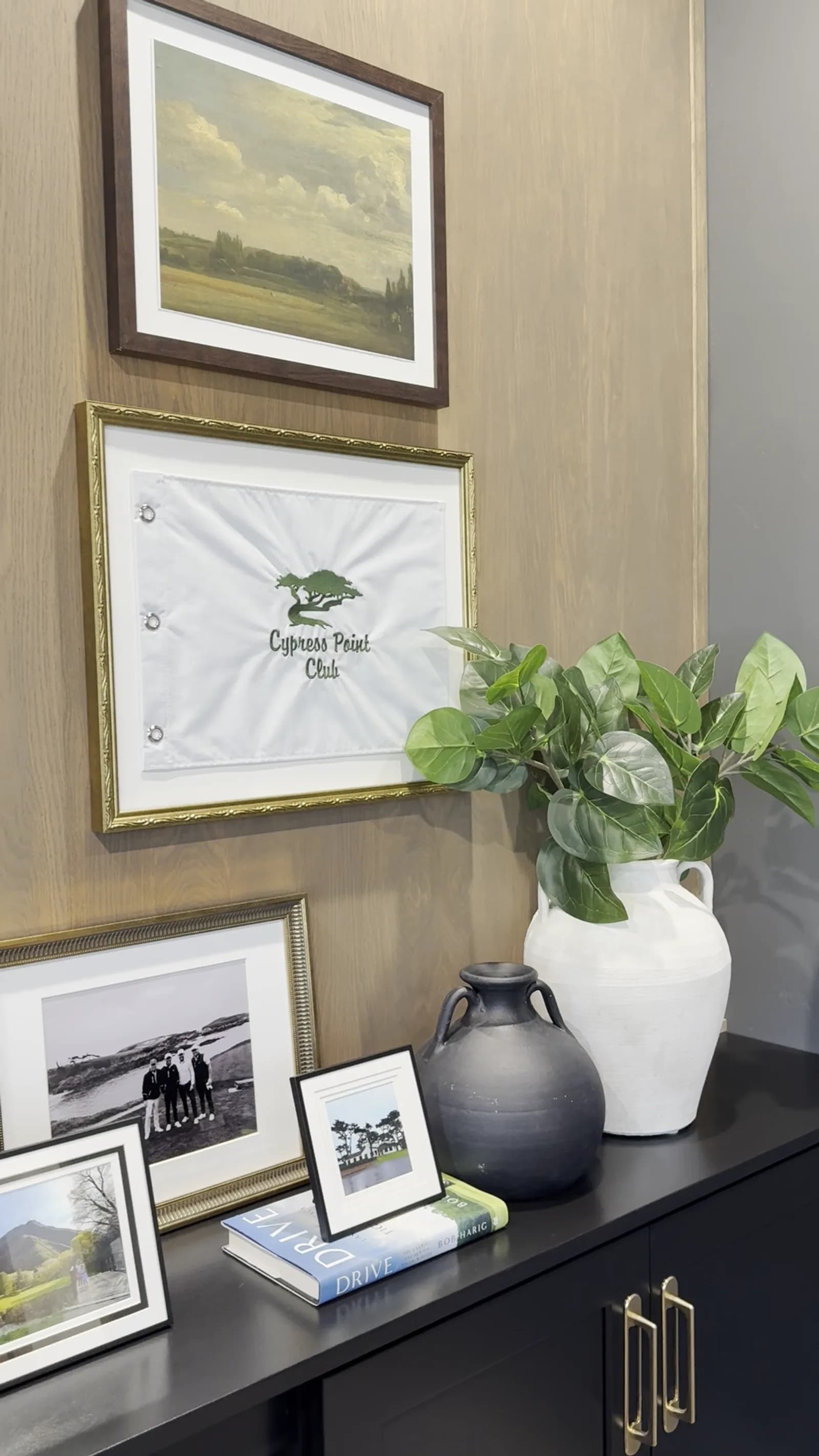 Wood-paneled home office with framed art, family photos, and styled black sideboard by BK Toolbox